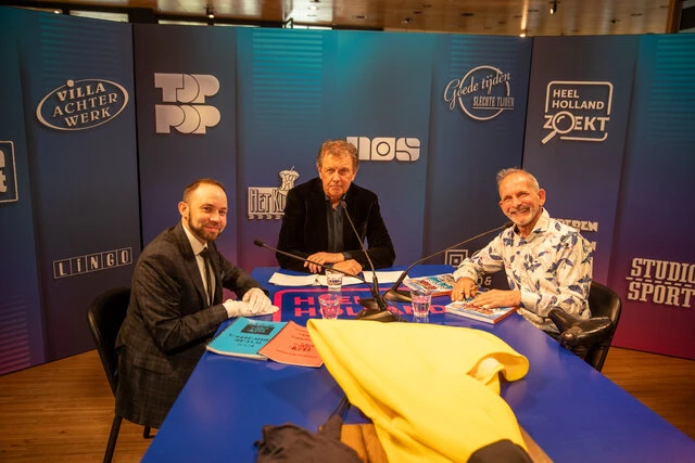 Presentator Robert ten Brink met conservator Wytze Koppelman en schenker Johan Vlemmix met zijn Ter Land, Ter Zee en In de Lucht-collectie