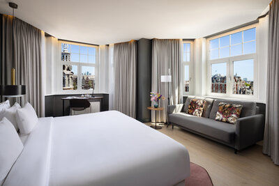 NH_Collection_Amsterdam_Flower_Market_Rooms_Junior_Suite_Overview_Double_Bed_Sofa_Flower_Pillows_Vase_With_Flowers_Light_On-4096x2732