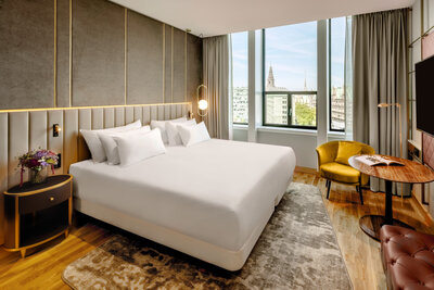 NH_Collection_Copenhagen_Room_superior_with_views_curtains_open_king_size_bed_with_yellow_chair_and_table-4080x2722