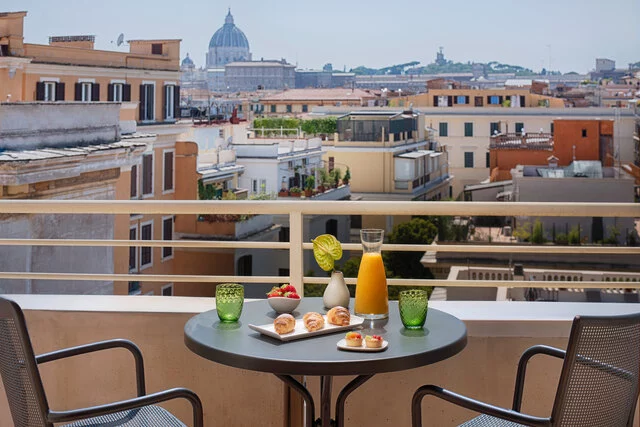 NH_Collection_Giustiniano_Room_Suite_Terrace_City_City_View_Daylight_Table_Chairs_Orange_Juice_Glasses_Pastries_Horizontal_Shoot