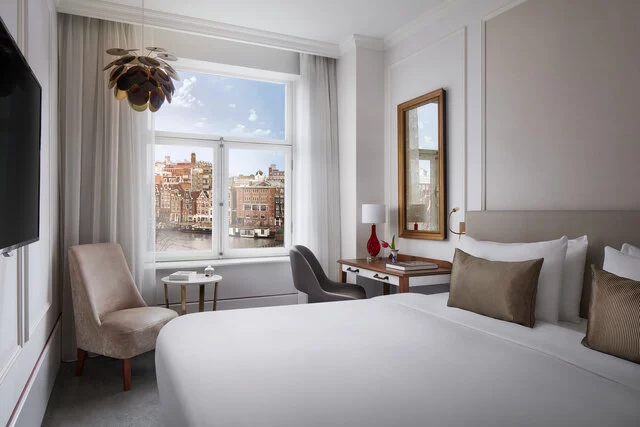 Tivoli_Doelen_Amsterdam_Guest_Room_Superior_Room_Canal_View_King_size_bed_beige_chair_desk_Hanging_lamp_Books-8573x5716