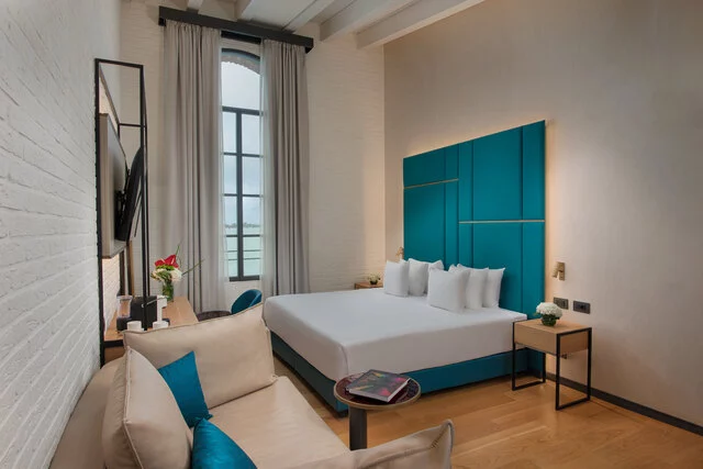 NH_Collection_Murano_Villa_Junior_Suite_Room_Laguna_Views_Bed_Pillows_Sofa_Tables_Flowers_TV_Window
