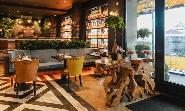 NH_Collection_Madison_Avenue_Restaurant_Serafina_Plants_Pizza_Oven_Entrance_Daylight_Flowers_Chairs_Bottles