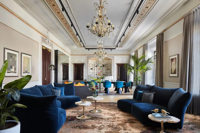 NH_Collection_Helsinki_Grand_Hansa_Room_Presidential_Suite_general_view_living_and_dining_area_fireplace_turquoise_couch_chairs_chandelier